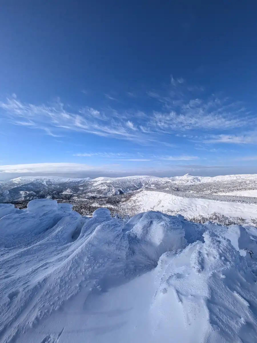 Summit view over snow cornices, frosted forest and a sea of clouds